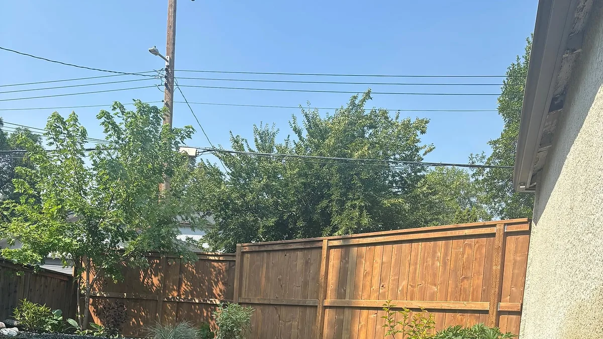 Tidy Winnipeg backyard with edged lawn, rock bed, shrubs and a stained wood fence